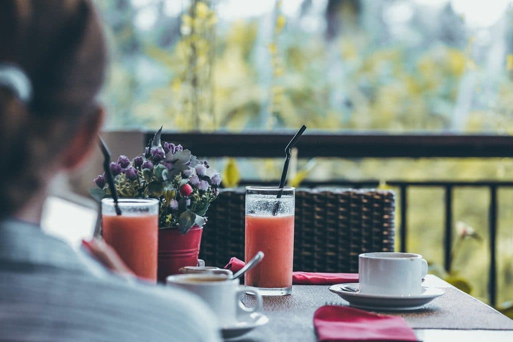 Young woman drinking a cup of coffee in the morning with the jungle view during luxury vacation in Bali island.