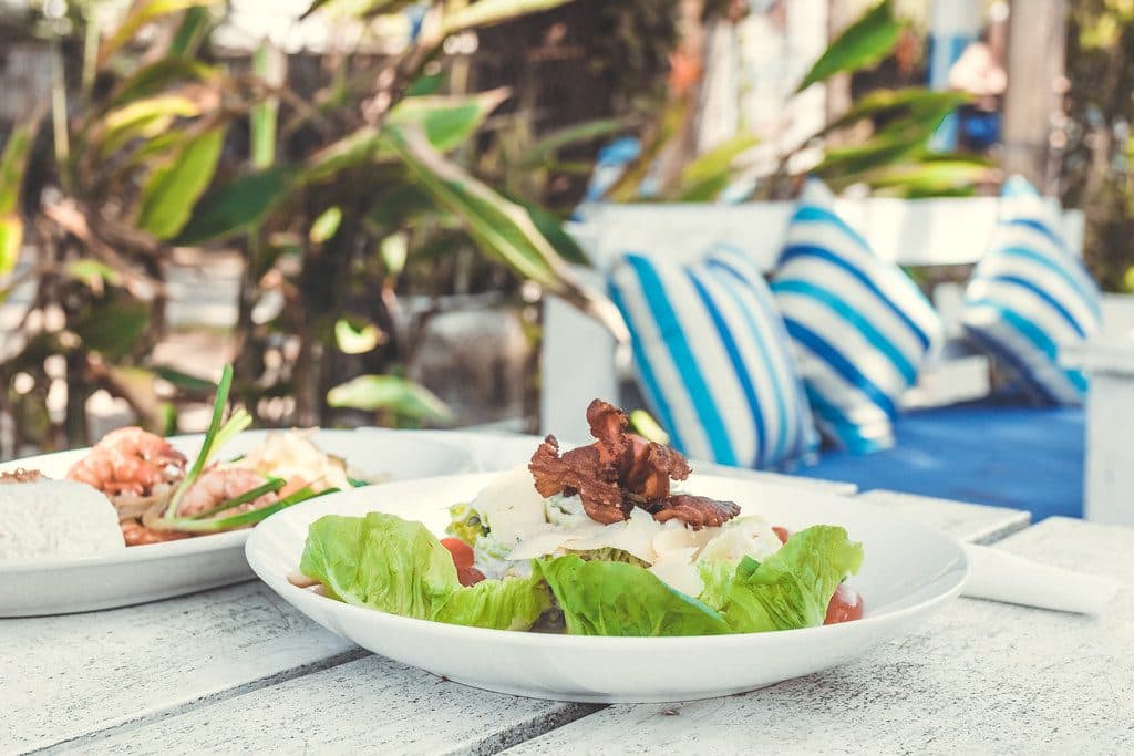 Caesar Salad on a white wooden table in the beach cafe, Bali island.